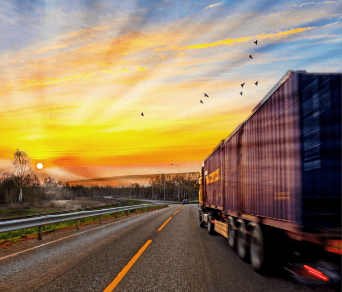 truck driving into beautiful sunset with mountains in distance
